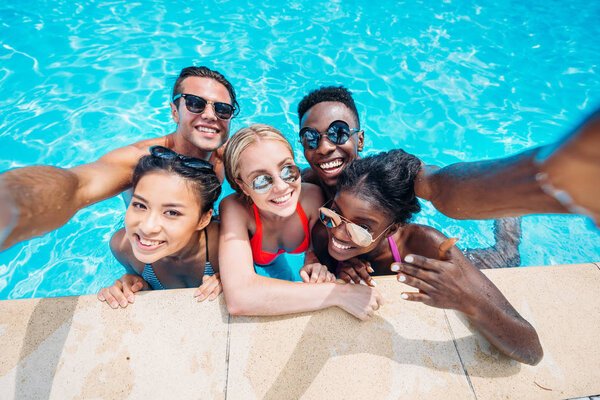 multiethnic people taking selfie in pool 