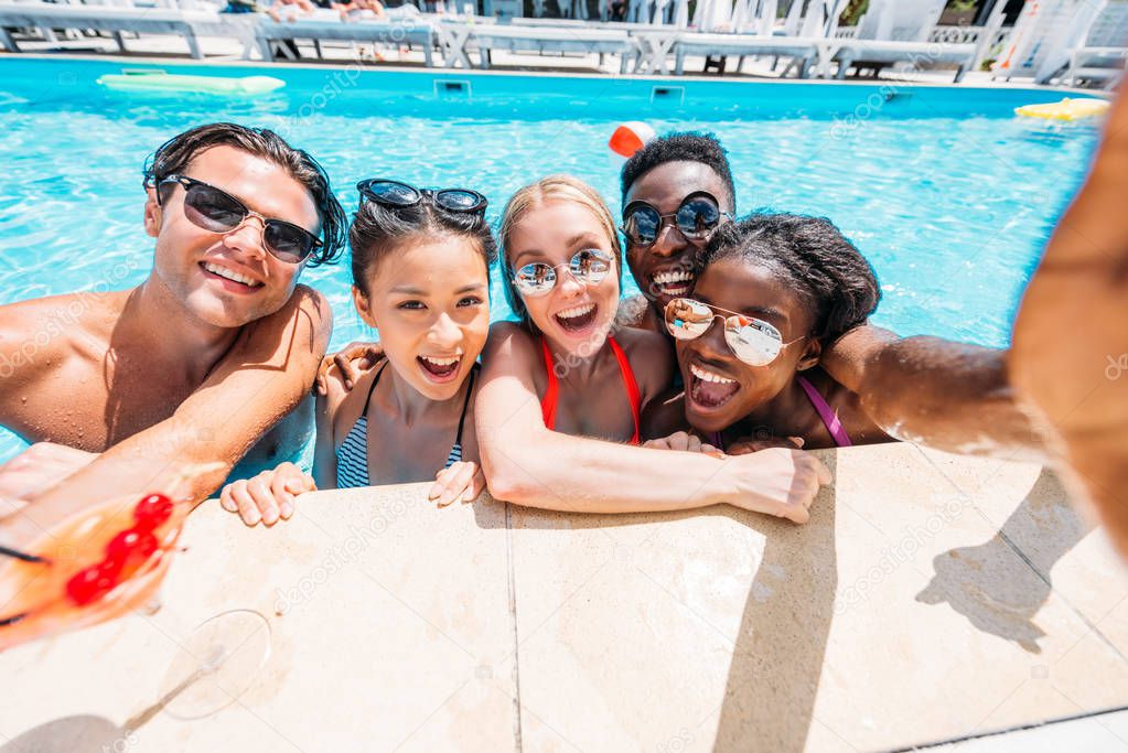 multiethnic people taking selfie in pool 