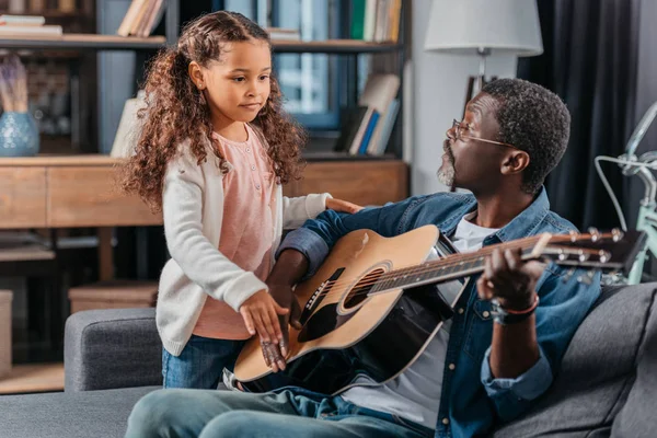 Uomo che suona la chitarra con la figlia a casa — Foto Stock