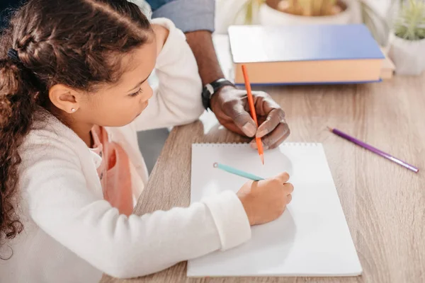 African american girl drawing with father Stock Photo