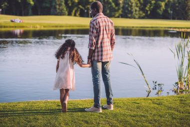 girl and grandfather standing near lake clipart