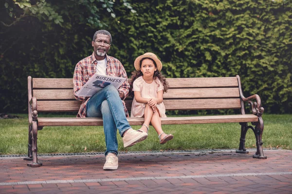 Granddaughter and her grandfather sitting on bench — Stock Photo, Image