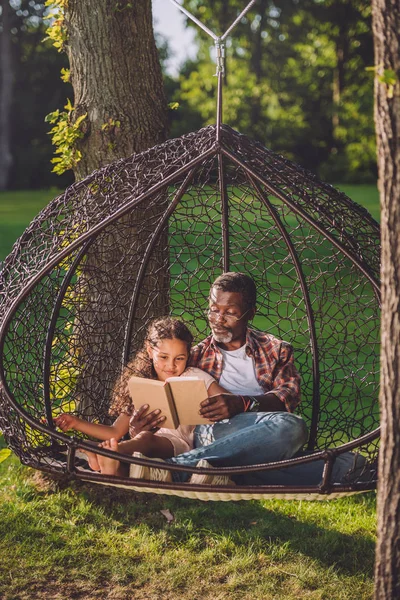 Granddaughter and grandfather reading book — Stock Photo, Image