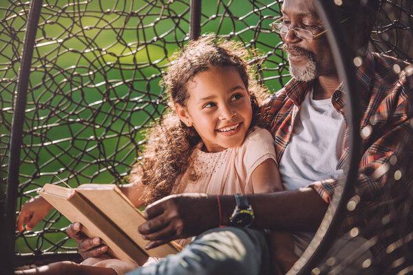 granddaughter and grandfather reading book 