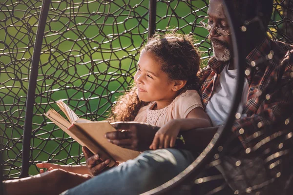 Девочка и дедушка читают книгу — стоковое фото