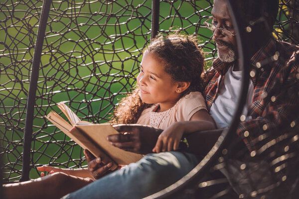 girl and grandfather reading book 