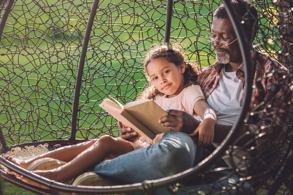 girl and granddad reading book 
