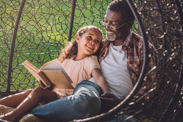girl and granddad reading book 