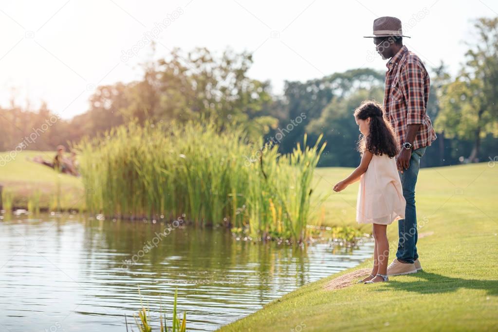 granddaughter and grandfather standing at lake