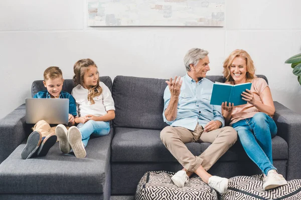 Familia con libro y portátil — Foto de Stock