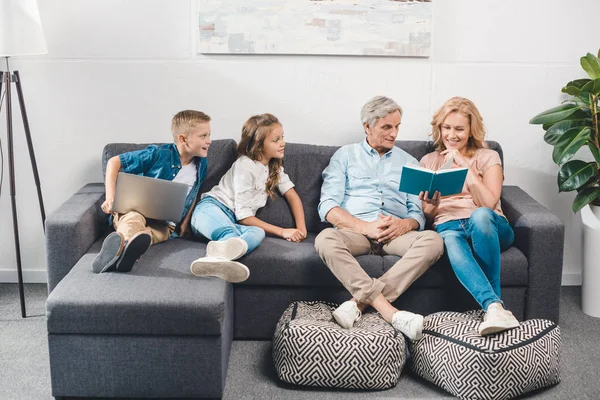 Family with book and laptop — Stock Photo, Image