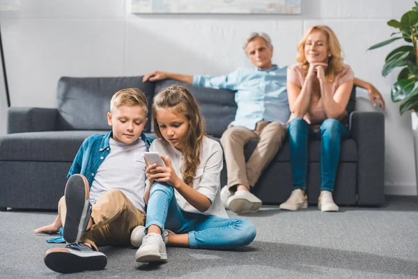 Grandchildren using smartphone — Stock Photo, Image