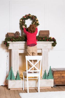 child hanging christmas wreath at home clipart