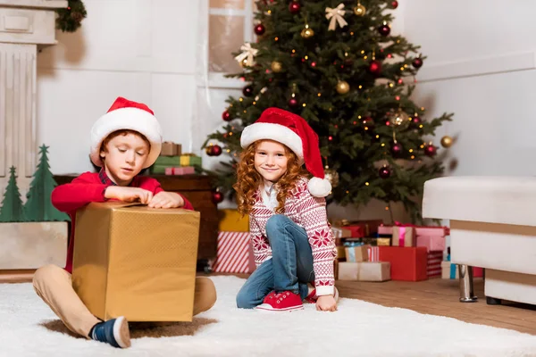 Děti v santa claus klobouky s dárkem — Stock fotografie