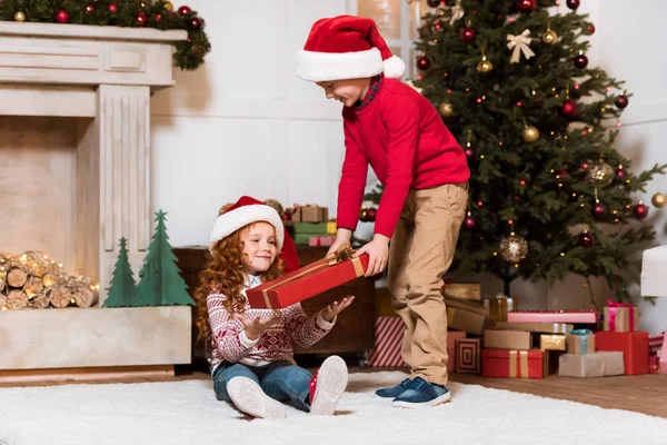 Děti v santa claus klobouky s dárkem — Stock fotografie