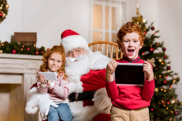 Papai Noel e crianças com dispositivos digitais — Fotografia de Stock