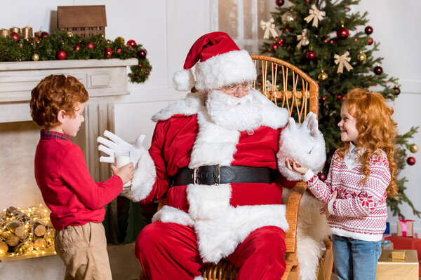 kids giving milk and cookie to santa