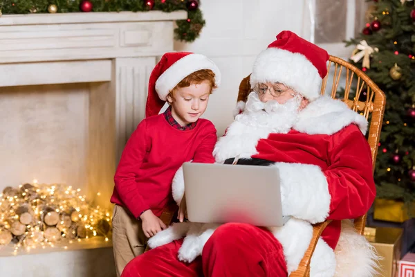 Jultomten och liten pojke med laptop — Stockfoto