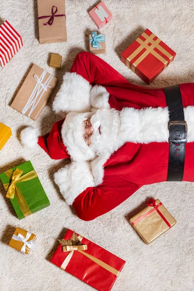 Weihnachtsmann liegt mit Geschenken auf dem Boden — kostenloses Stockfoto