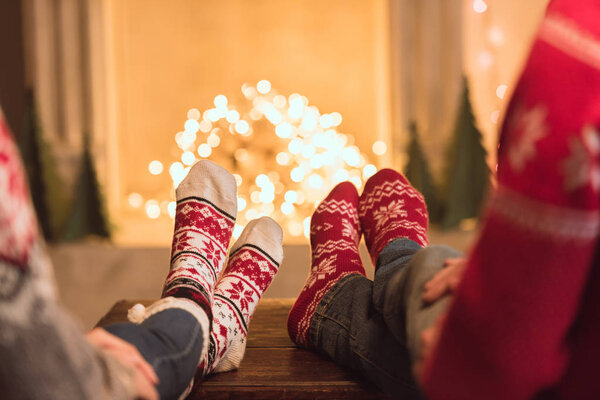 couple in knitted socks near fireplace