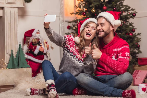 Coppia in cappelli di Babbo Natale prendendo selfie — Foto Stock