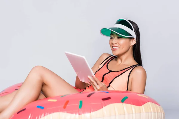 Woman on pool float with tablet