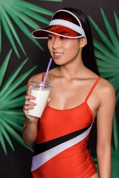 Woman in swimsuit and visor drinking milkshake — Free Stock Photo
