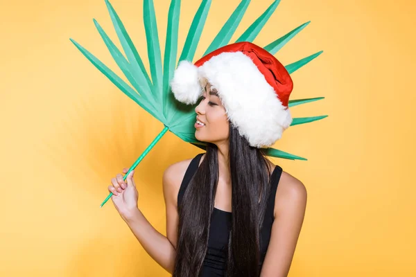 Mulher em santa chapéu com folha de palmeira — Fotografia de Stock