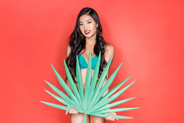 Woman in swimsuit holding palm leaf — Stock Photo, Image