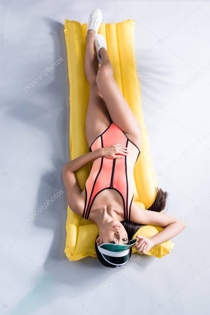woman in swimsuit lying on pool mattress