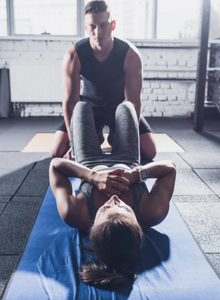 Mujer haciendo ejercicios abdominales con entrenador — Foto de Stock