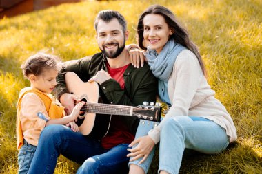 Sonbahar parkında oturan aile