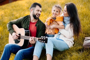 Genç adam aile ile gitar çalmak