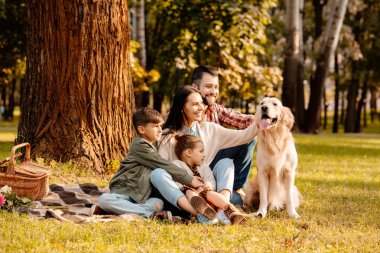 Family on picnic petting dog clipart