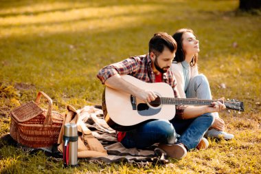 young man with girlfriend playing guitar clipart