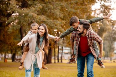 Parents giving children piggyback ride clipart