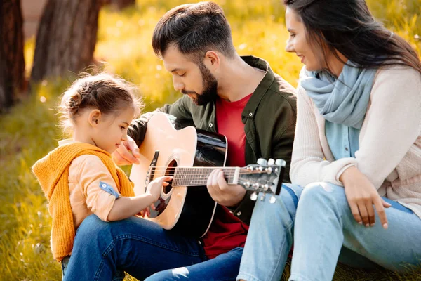 Genç adam aile ile gitar çalmak