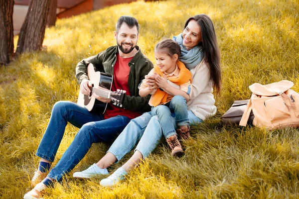 Ung man spelar gitarr med familj — Stockfoto