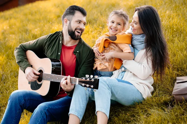 Молодой человек играет на гитаре с семьей — стоковое фото