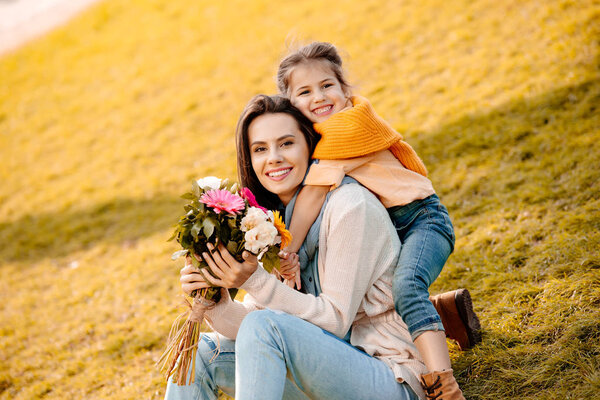 Woman holding flowers with daughter 