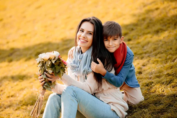 Zoon met moeder bedrijf bloemen — Stockfoto