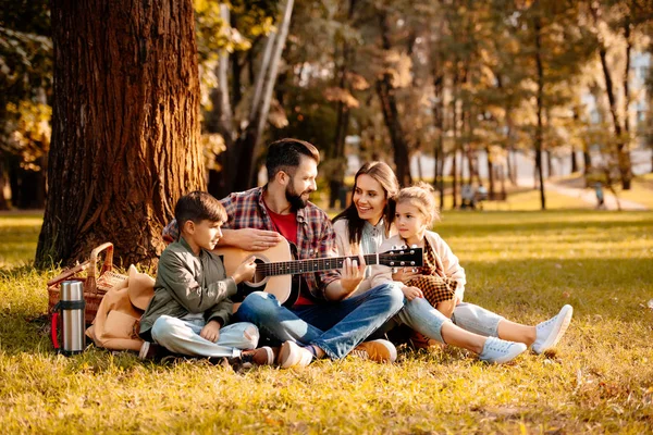 Семья на пикнике играет на гитаре — стоковое фото