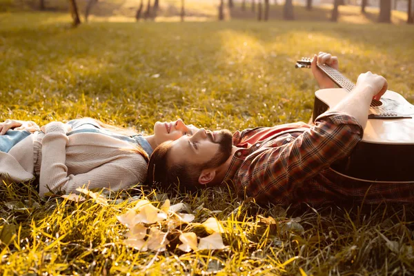 Пара лежить на траві з гітарою — стокове фото