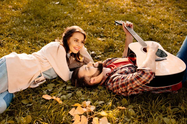 躺在草地上与吉他的夫妇 — 图库照片