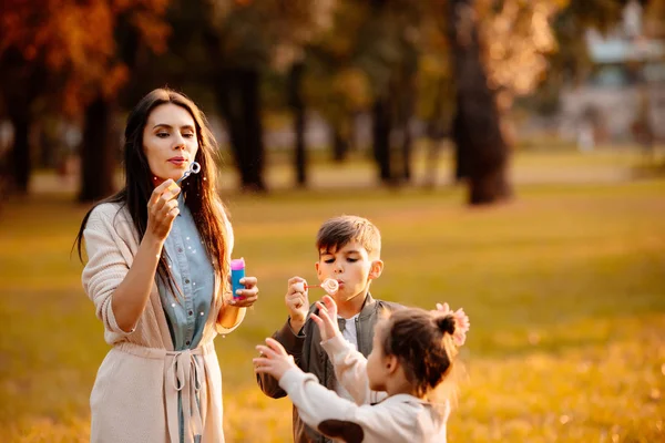 Mother with children blowing bubbles — Stock Photo, Image