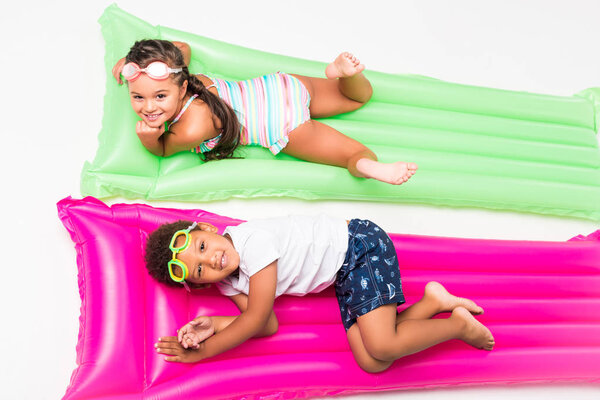 kids in swimwear on swimming mattresses  