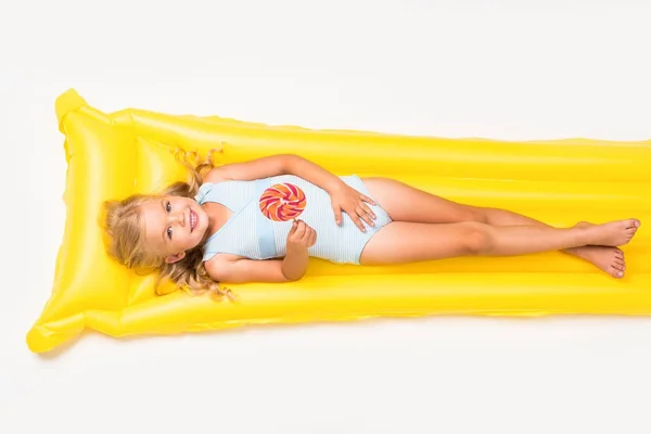 Kid with lollipop on swimming mattress — Stock Photo, Image