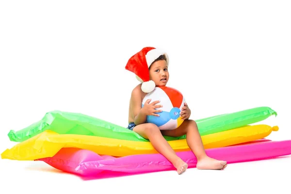 Boy in santa hat on swimming mattresses — Free Stock Photo