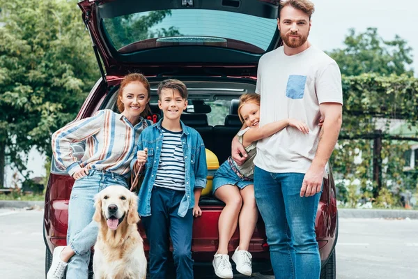 Family with dog standing next to car — Stock Photo, Image