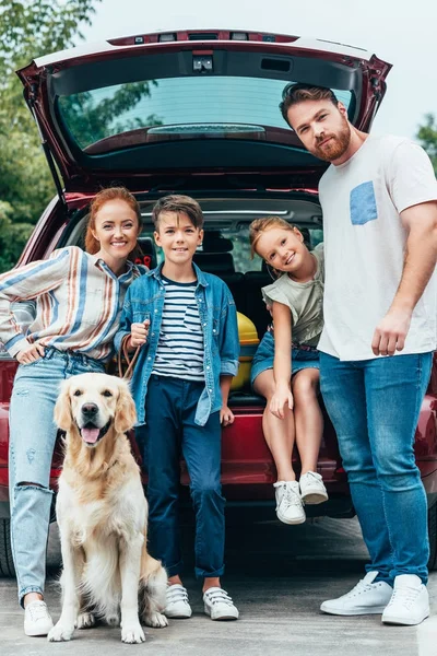 Family with dog standing next to car — Stock Photo, Image